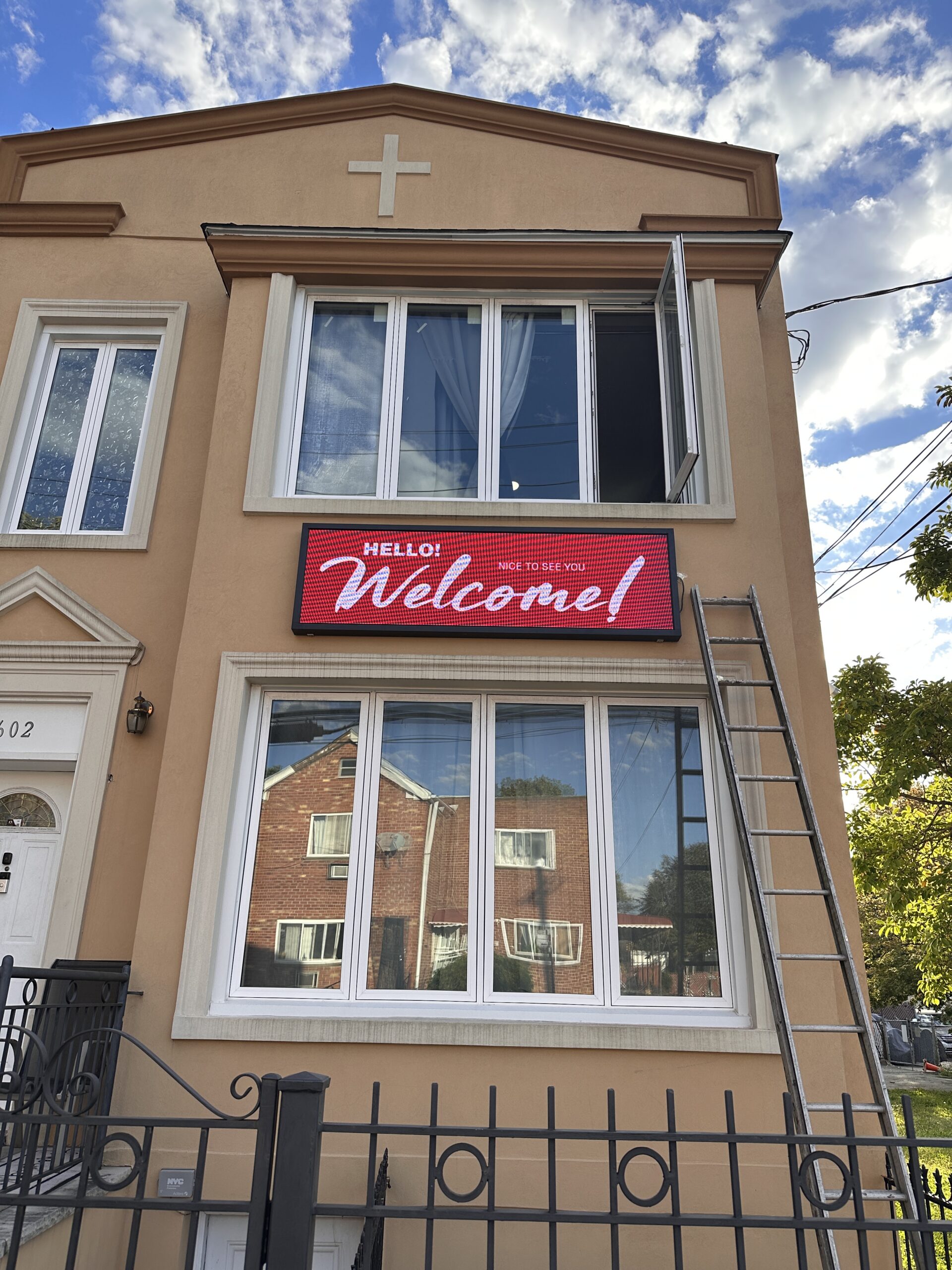 Wall-mounted outdoor LED sign displaying a welcome message on a Brooklyn building.